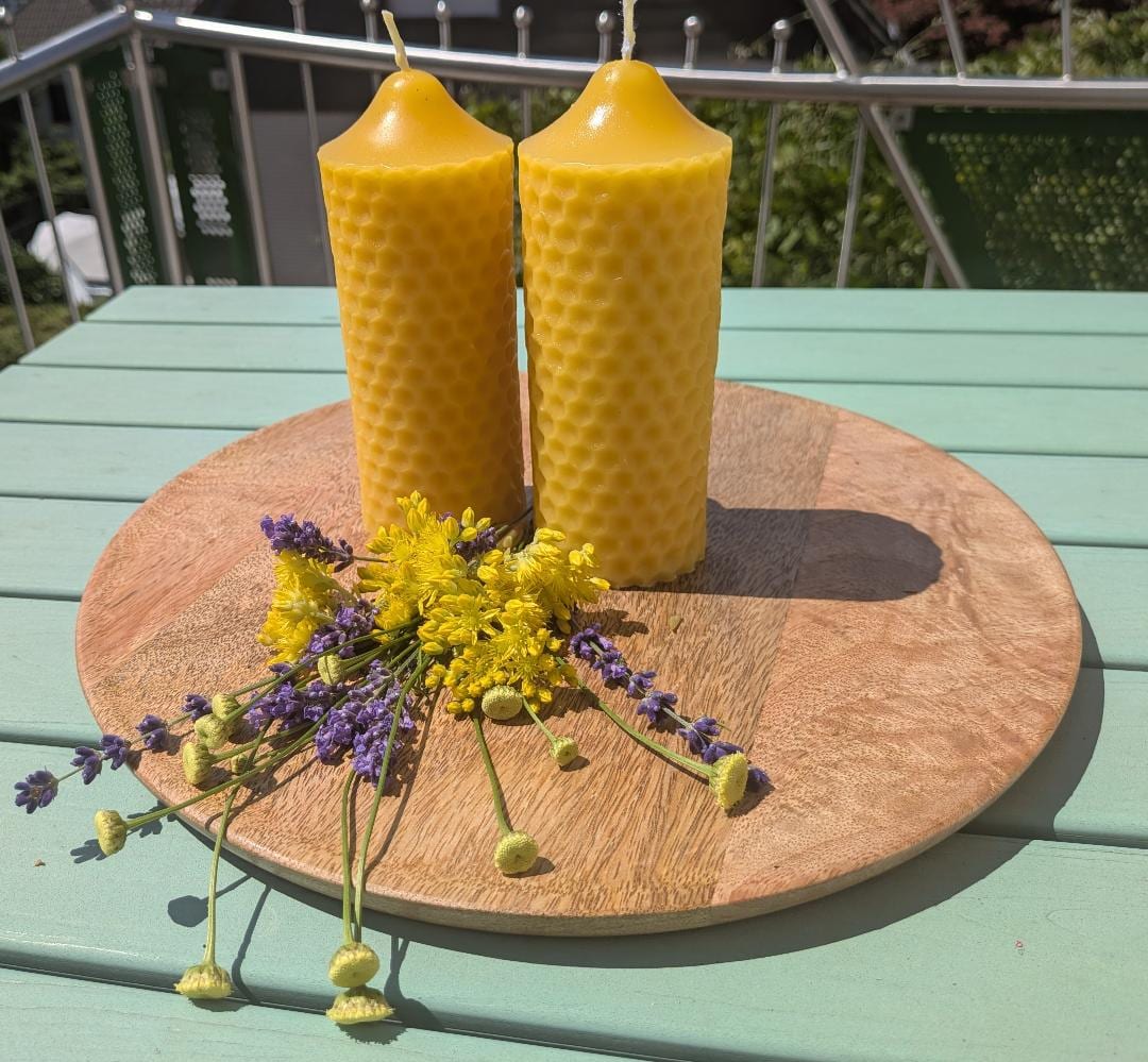 Zwei schlanke Bienenwachskerzen mit Wabenrelief auf Holzscheibe, mit Lavendel und Wiesenblumen